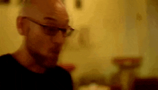 a bald man wearing glasses is sitting at a table .