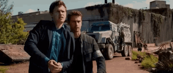a couple of men standing next to each other in front of a truck .