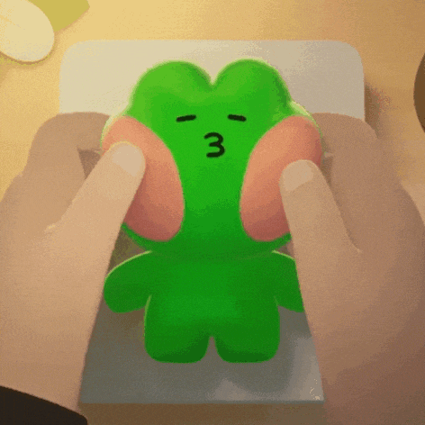 a person is holding a green frog with the number 3 on it 's face