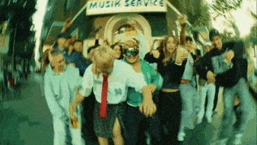a group of people are dancing in front of a sign that says muzik service