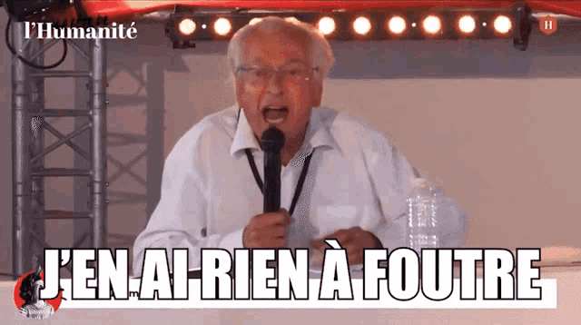 a man speaking into a microphone with the words j'en ai rien a foutre written below him
