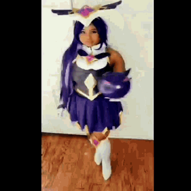 a little girl in a costume is standing on a wooden floor holding a cat .