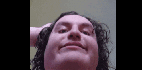 a close up of a person 's face with curly hair making a face .