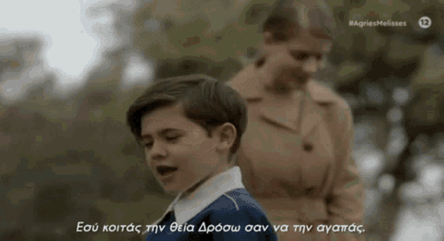 a young boy singing in front of a woman with a caption in greek