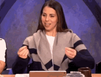 a woman in a sweater is sitting at a table with a laptop