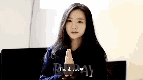 a woman says thank you with her hands folded in front of her face