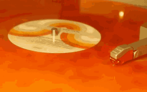 a record player is playing an orange record with a needle on it .
