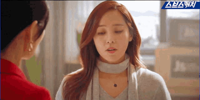 a woman with a choker around her neck is talking to another woman in a kitchen