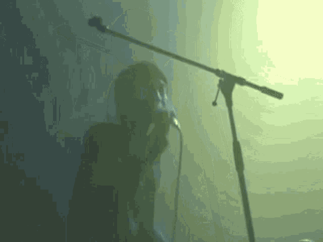 a person is singing into a microphone on a stage in a dark room .