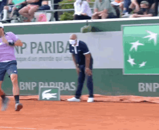 a man in a purple shirt is running on a tennis court