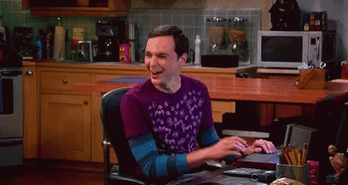 a man wearing a purple shirt is sitting at a desk in a kitchen