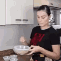 a woman is preparing food in a kitchen while holding a bowl .