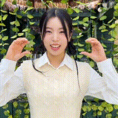 the girl is wearing a white vest and a white shirt and is standing in front of a green wall .