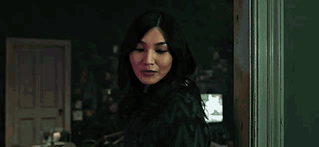 a woman is standing in a dark room in front of a door .