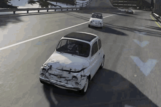 a white car with a black roof is driving down a highway