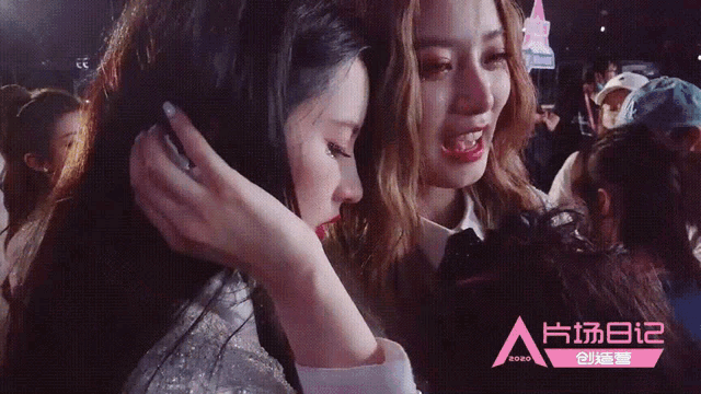 two women are hugging each other in front of a sign that says ' a '