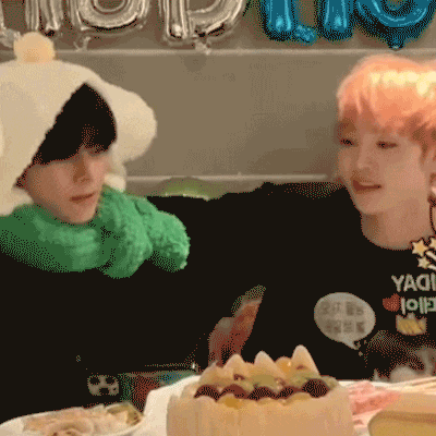 a boy wearing a yaoi shirt sits next to another boy