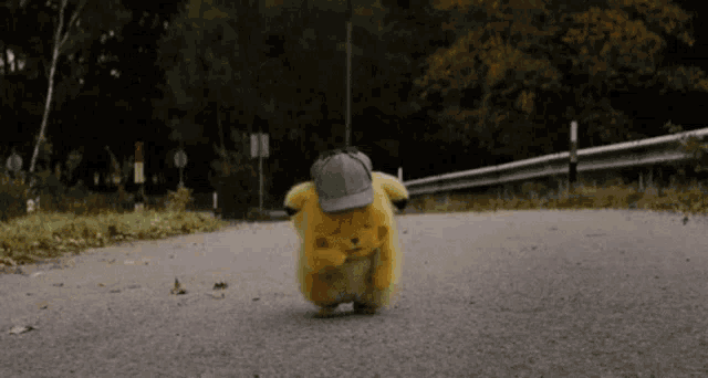 a small stuffed animal wearing a hat is walking down the road