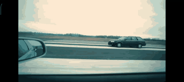 a car is driving down a highway with the rear view mirror showing a reflection of another car