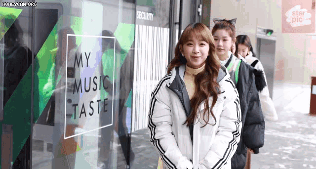 a group of girls are standing in front of a window that says my music taste