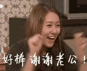 a woman is sitting on a couch with her fist in the air and smiling .