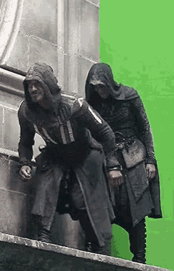 a man in a hood is standing next to another man in a hood on a green screen .