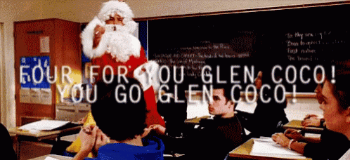 a man dressed as santa claus is standing in front of a classroom