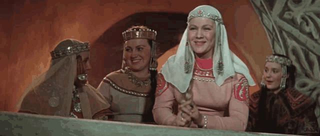a woman in a pink dress is surrounded by other women in traditional costumes