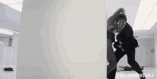 a man in a suit is fighting another man in a white room with the words mission impossible on the bottom