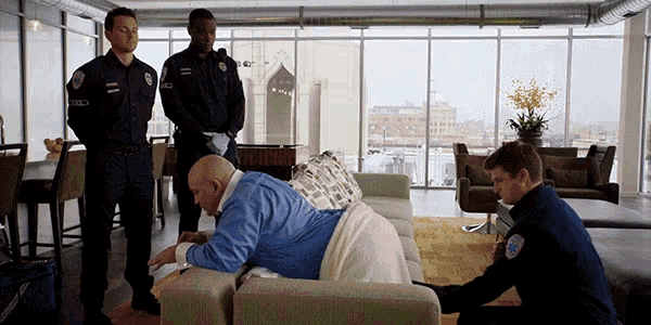 a man laying on a couch with two police officers standing around him