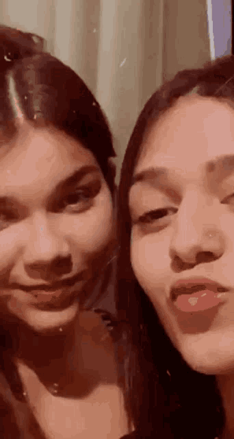 two young women are standing next to each other and making faces .