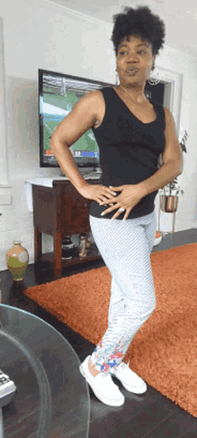 a woman is standing in front of a tv with a game on