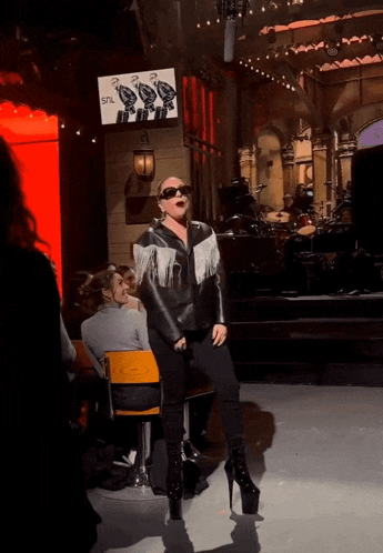 lady gaga is dancing on stage in front of a snl sign
