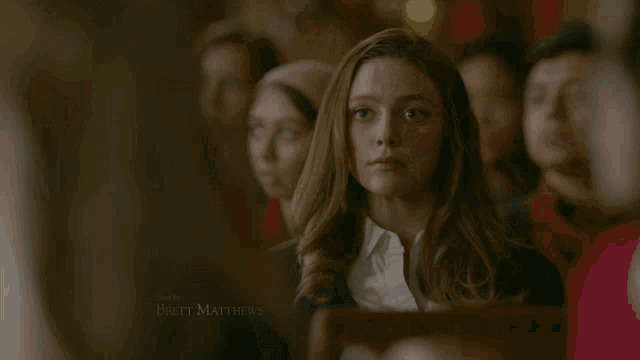a woman in a white shirt and black sweater with the name brett matthews