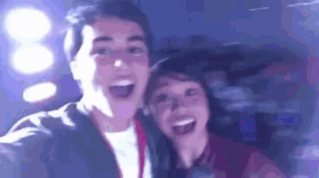 a man and a woman are taking a selfie in a dark room with their mouths open .