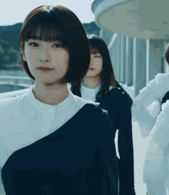 a group of young women are standing next to each other and one of them is wearing a white shirt and a black top .