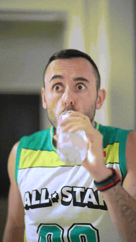 a man wearing an all star jersey drinking from a cup
