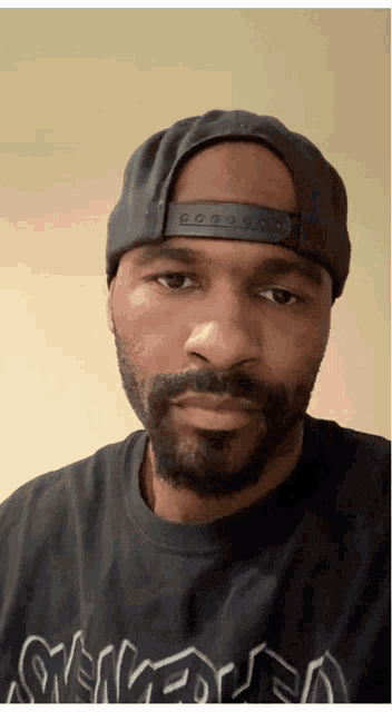 a man with a beard wearing a hat and a shirt that says snk