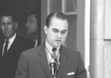 a man in a suit and tie is standing in front of a microphone