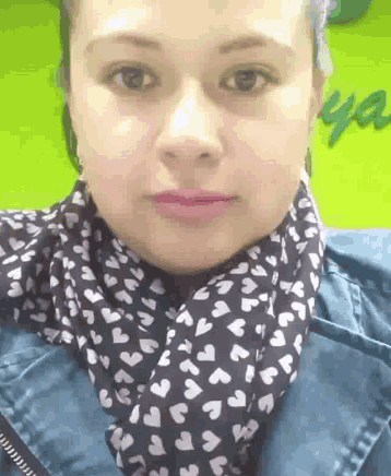 a woman wearing a scarf with hearts on it looks at the camera
