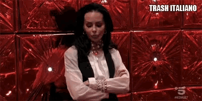 a woman is standing in front of a red wall and says oddio .