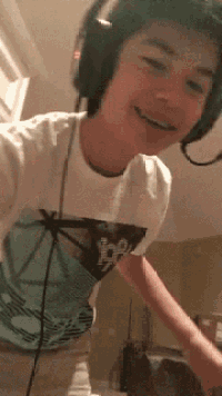 a young boy wearing headphones and a t-shirt is smiling .