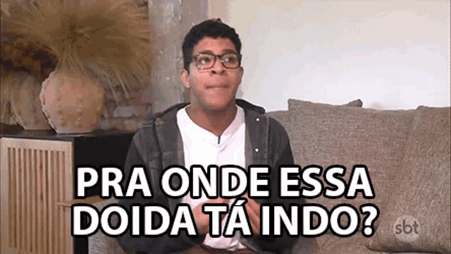 a man wearing glasses is sitting on a couch with a caption that says pra onde essa doida ta indo ?