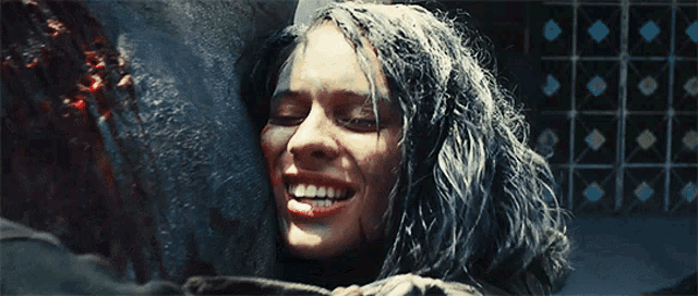 a woman is smiling with her eyes closed and her hair is covered in blood