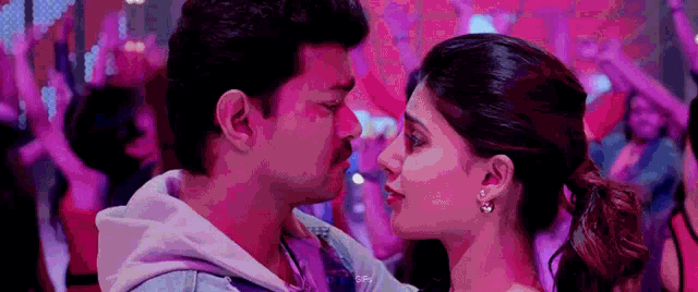 a man and a woman are looking into each other 's eyes while dancing at a party .