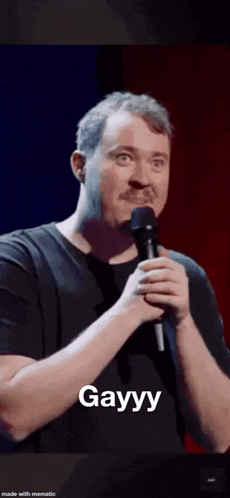 a man with a mustache is holding a microphone and says gayyy .