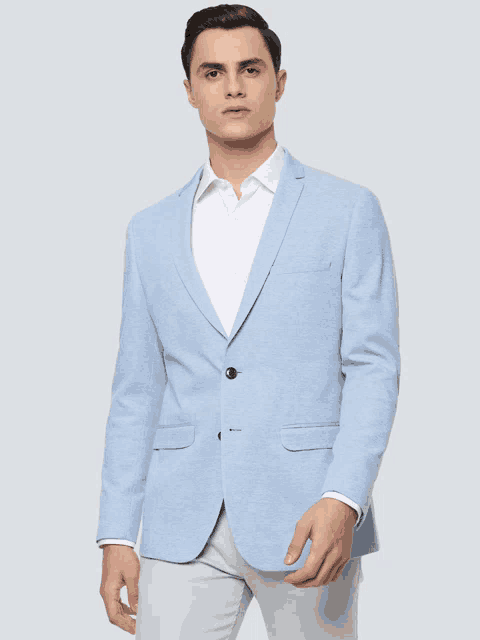 a man is wearing a light blue blazer and white pants