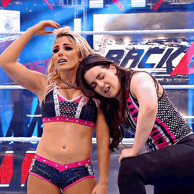 two female wrestlers are posing in front of a sign that says " back "