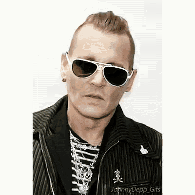 a man wearing sunglasses and a striped jacket is making a funny face .