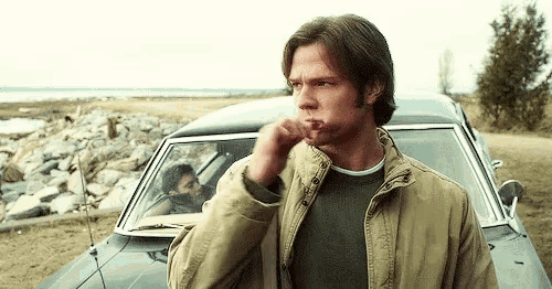 a man is brushing his teeth in front of a car